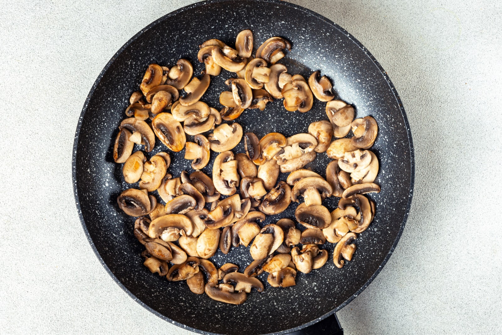 Sautéing mushrooms in a black skillet.