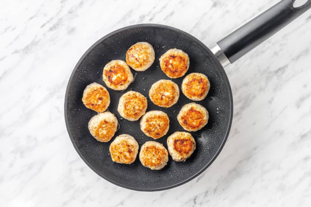 Seared meatballs in a skillet.