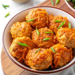 Serving meatballs with tomato sauce in a bowl with chopped green onion garnish.