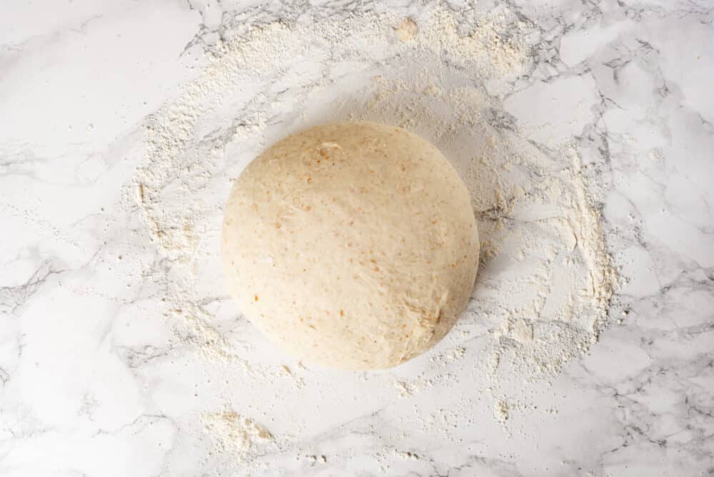 Shaped round bread dough on a flour surface.