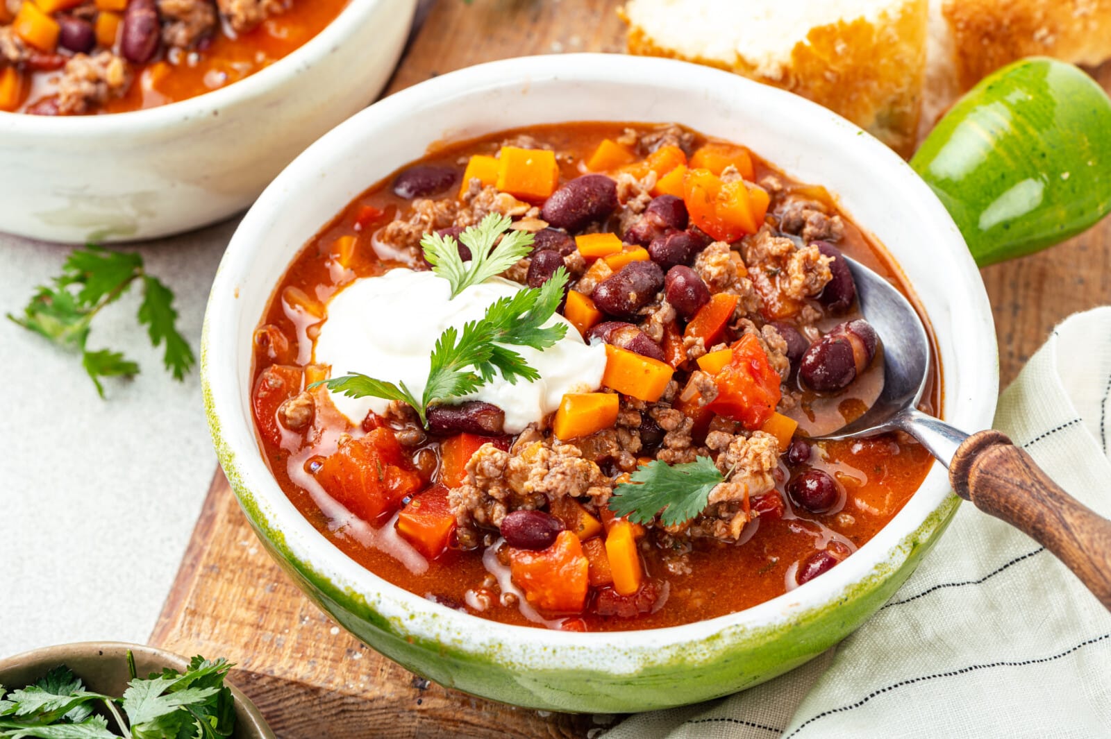 chili read ing a serving bowl with sour cream and fresh cilantro.