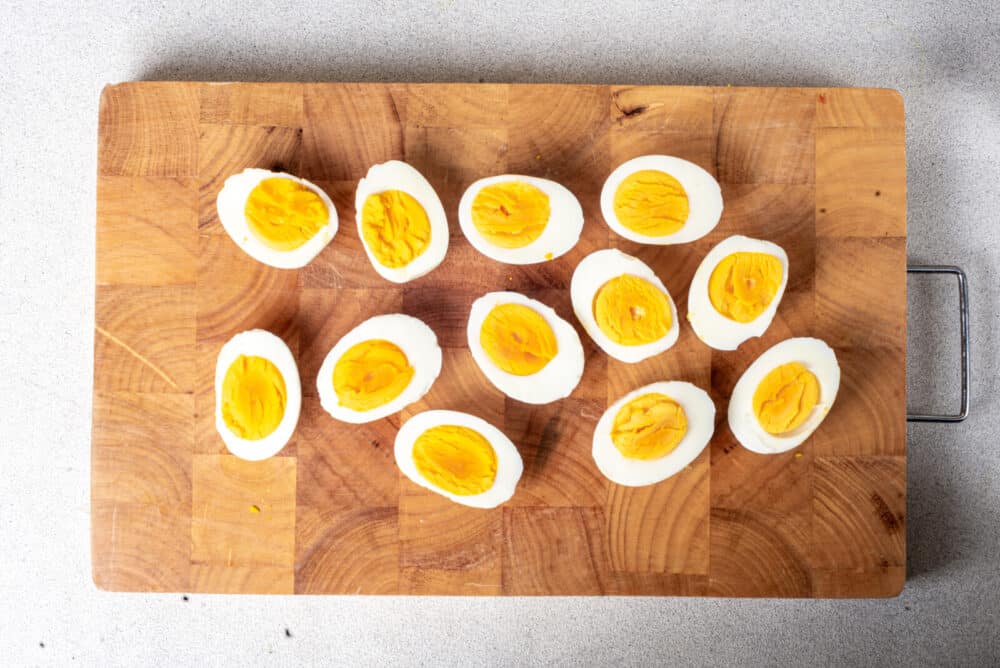 Boiled eggs sliced in half on a wooden board.