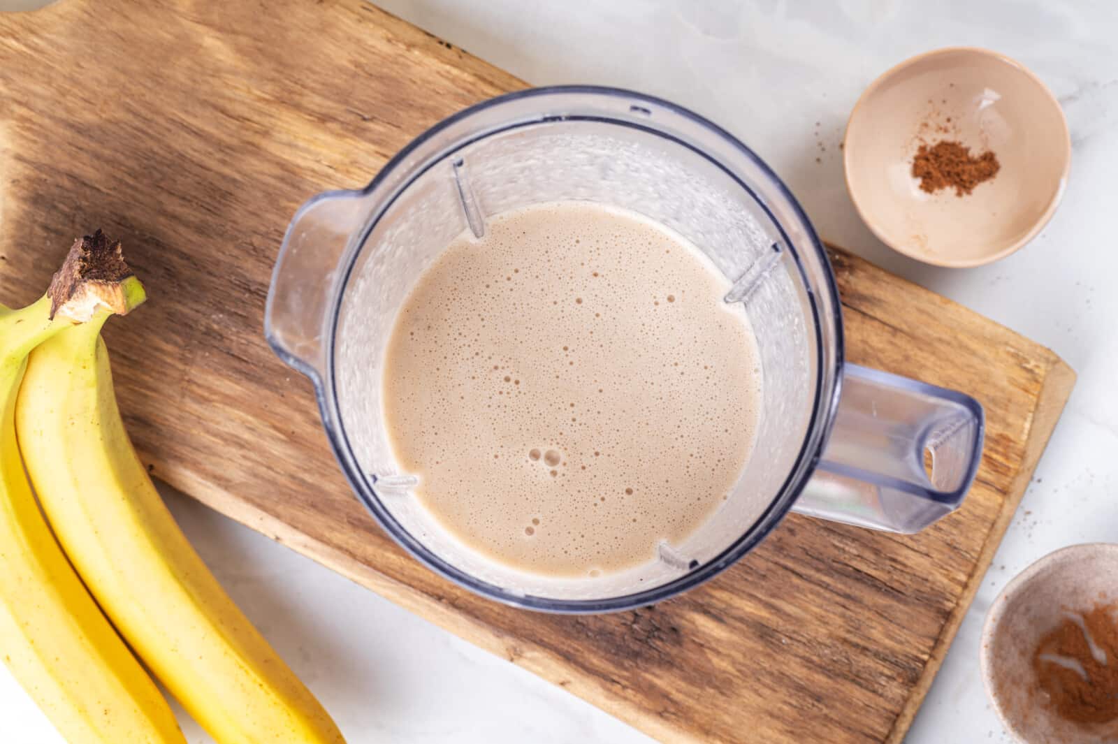 Smoothie blended in a blender on a wooden board.