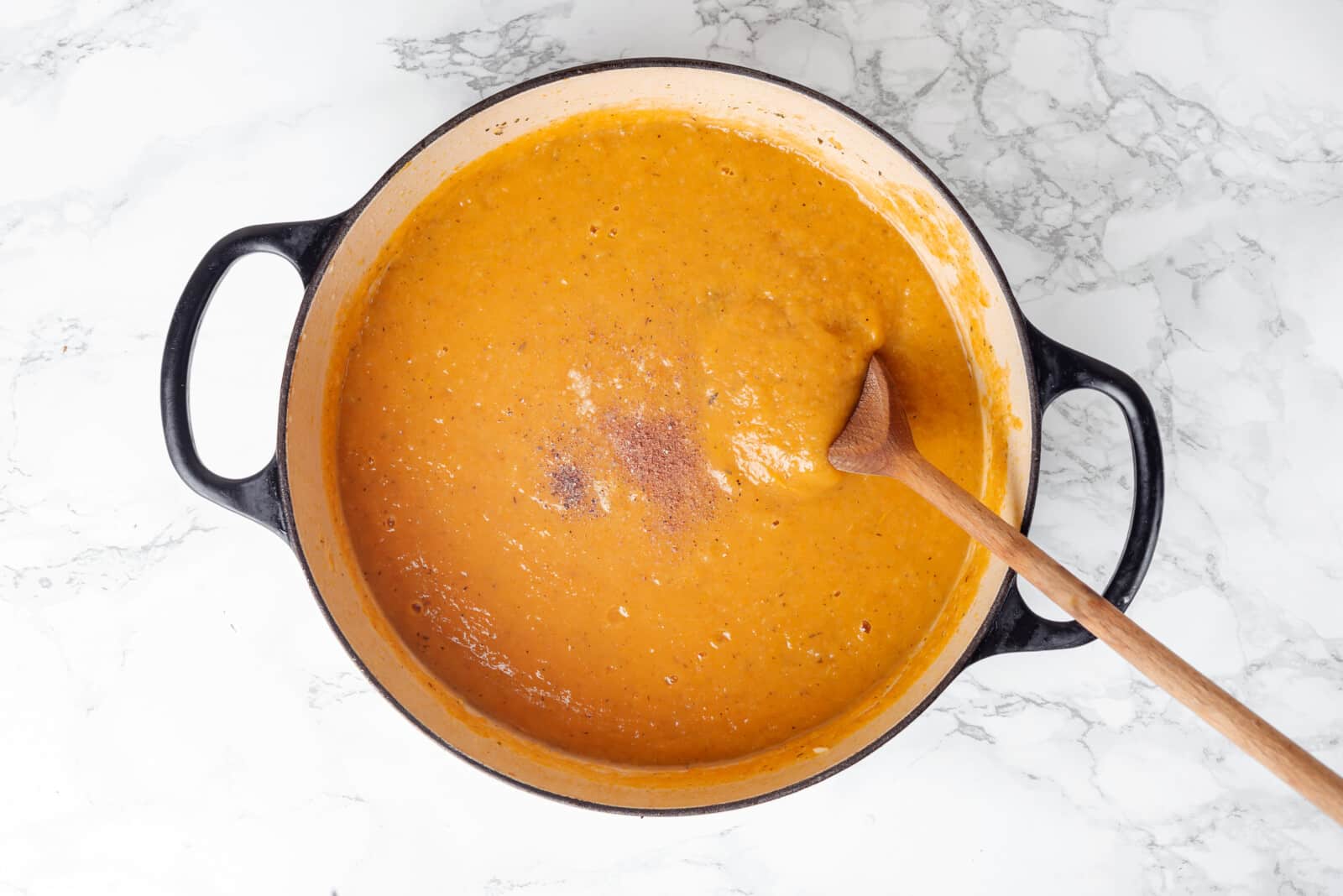 Squash soup in a large pot with seasonings on top.