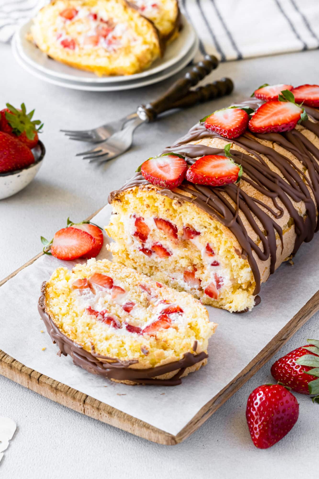 Strawberry cake roll on a wooden board for serving.