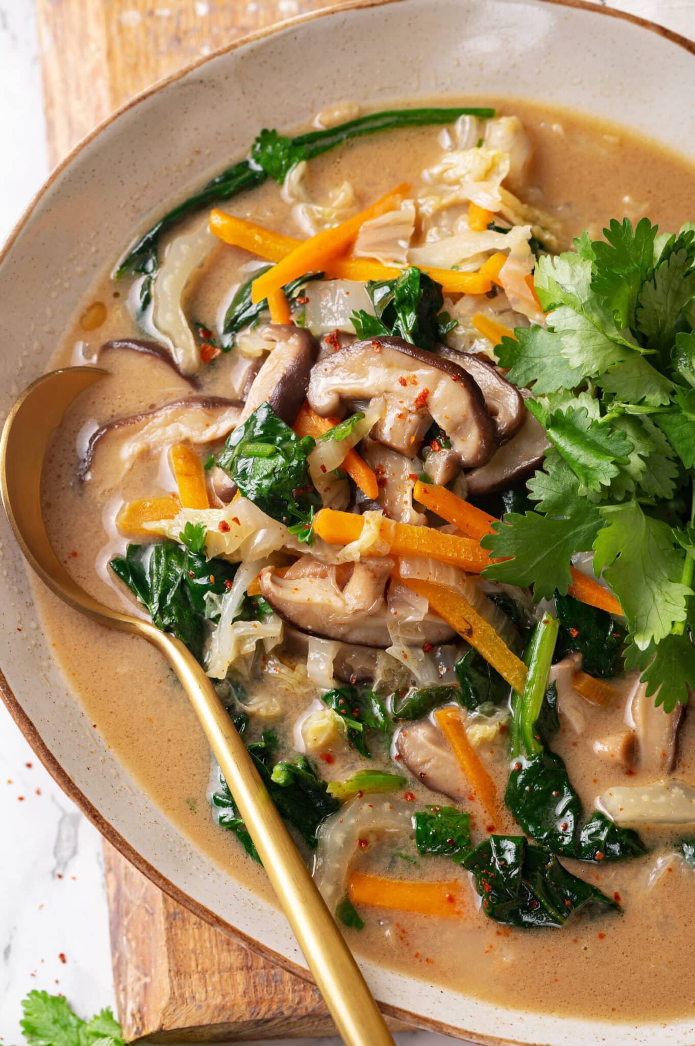 Thai coconut vegetable soup in a bowl with a gold spoon.