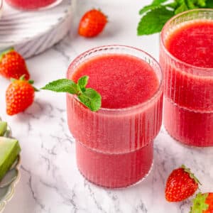 Watermelon smoothie with strawberries blended in and on the side.