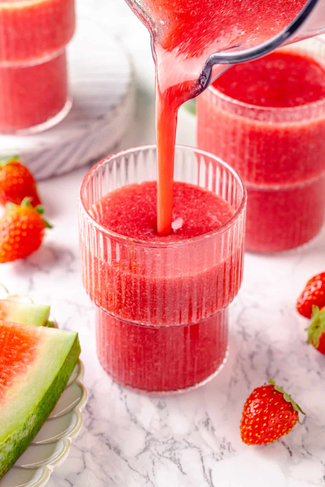 Watermelon strawberry smoothie being poured into a glass from the blender.