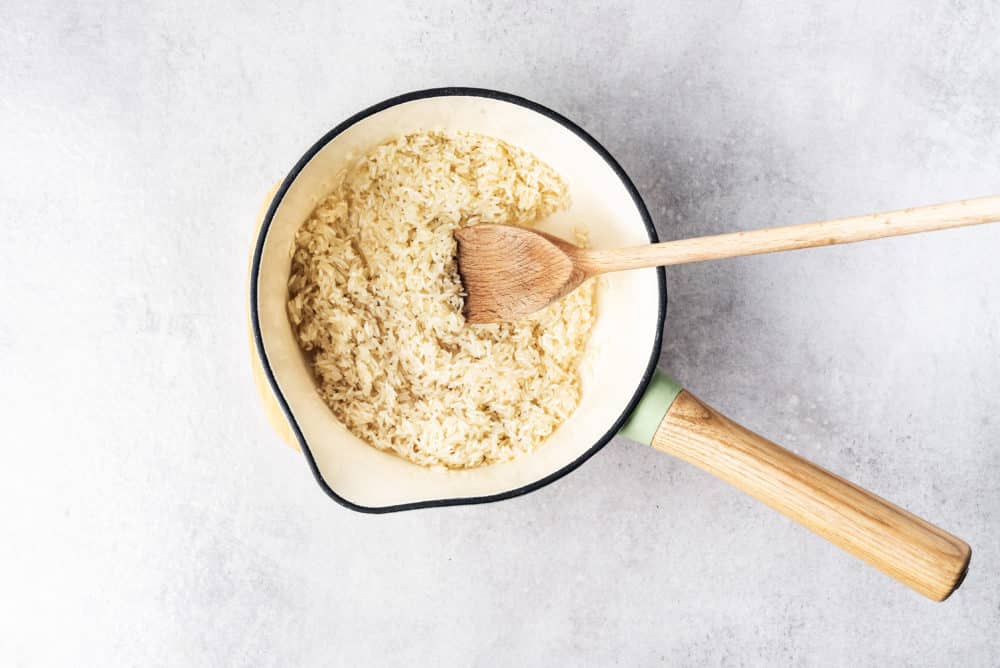 a saucepan filled with rice and a wooden spoon.