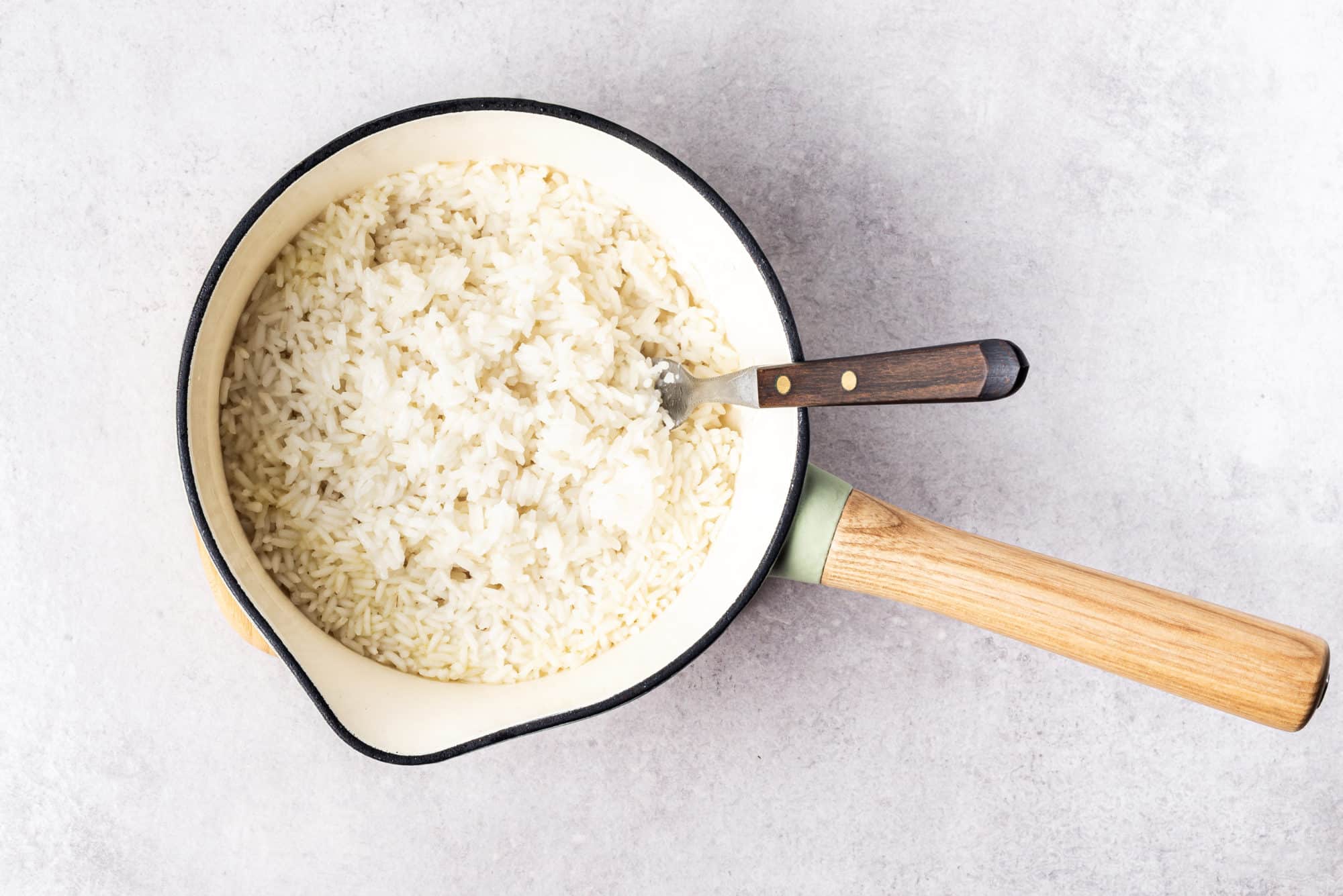 a pot filled with rice and with a fork.