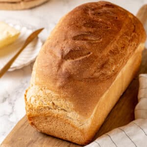 Whole wheat bread loaf freshly baked on a wooden board.