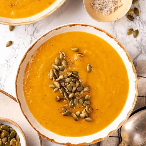 Bowls with squash soup and pumpkin seeds on top ready to eat.