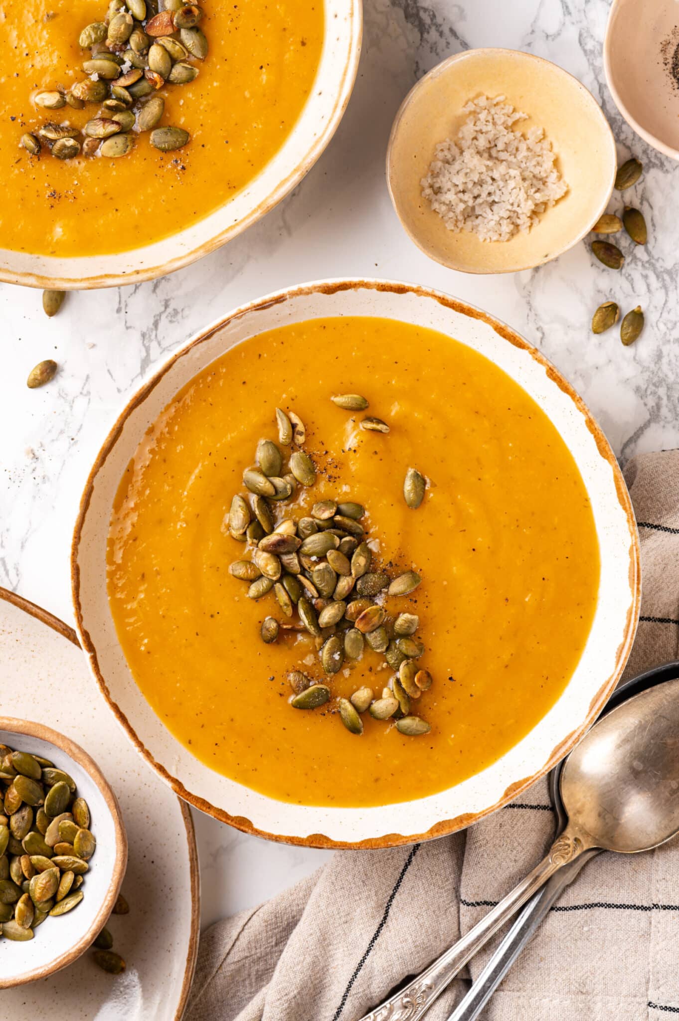 Bowls with squash soup and pumpkin seeds on top ready to eat.