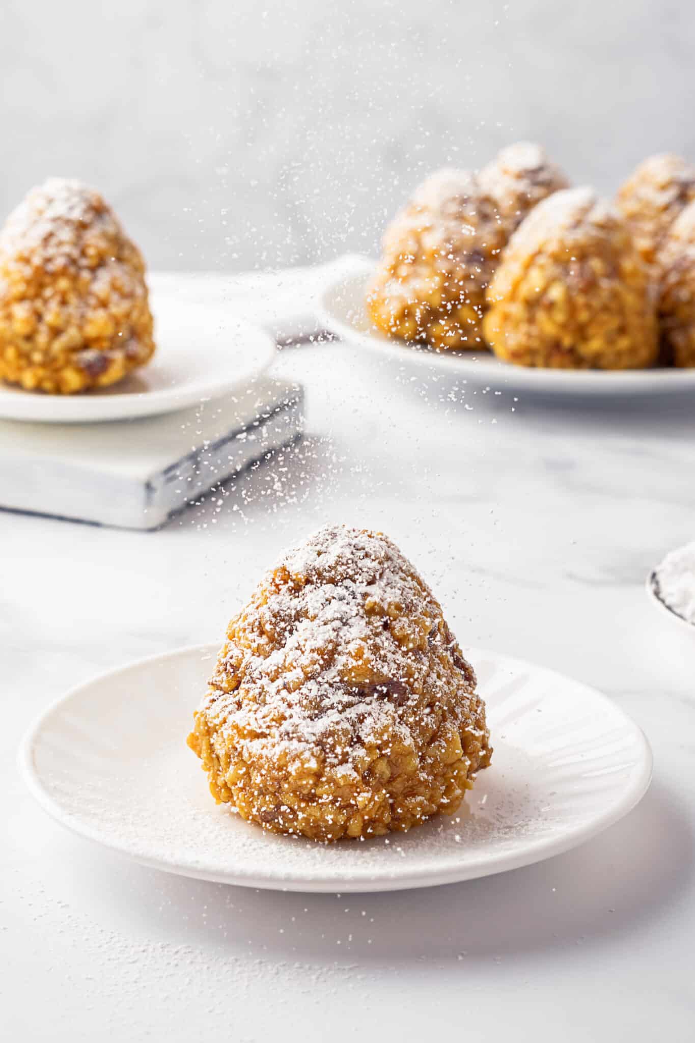 Sweet winter trees on a white plate being dusted with powdered sugar.