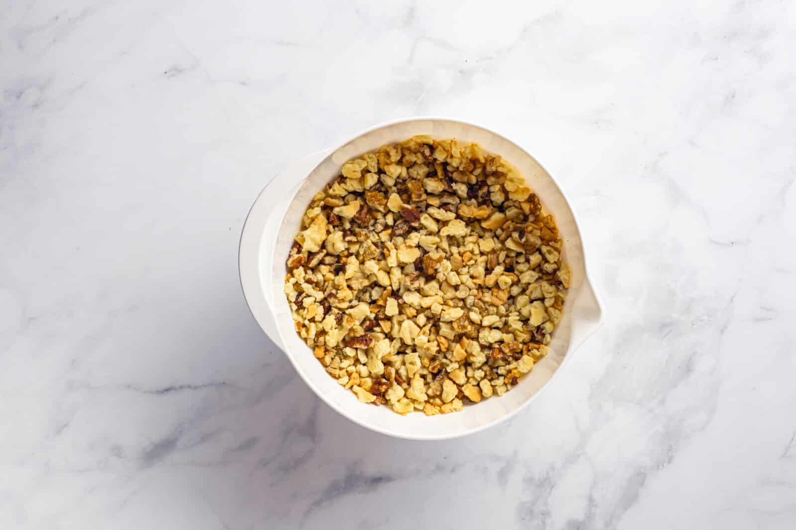 Grated dough from winter trees in a white bowl, mixed with chopped walnuts.