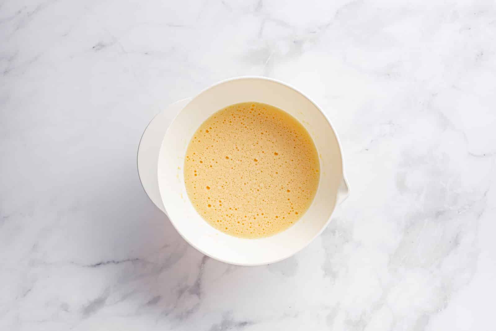 Eggs, sugar, and melted butter mixed in a white bowl.