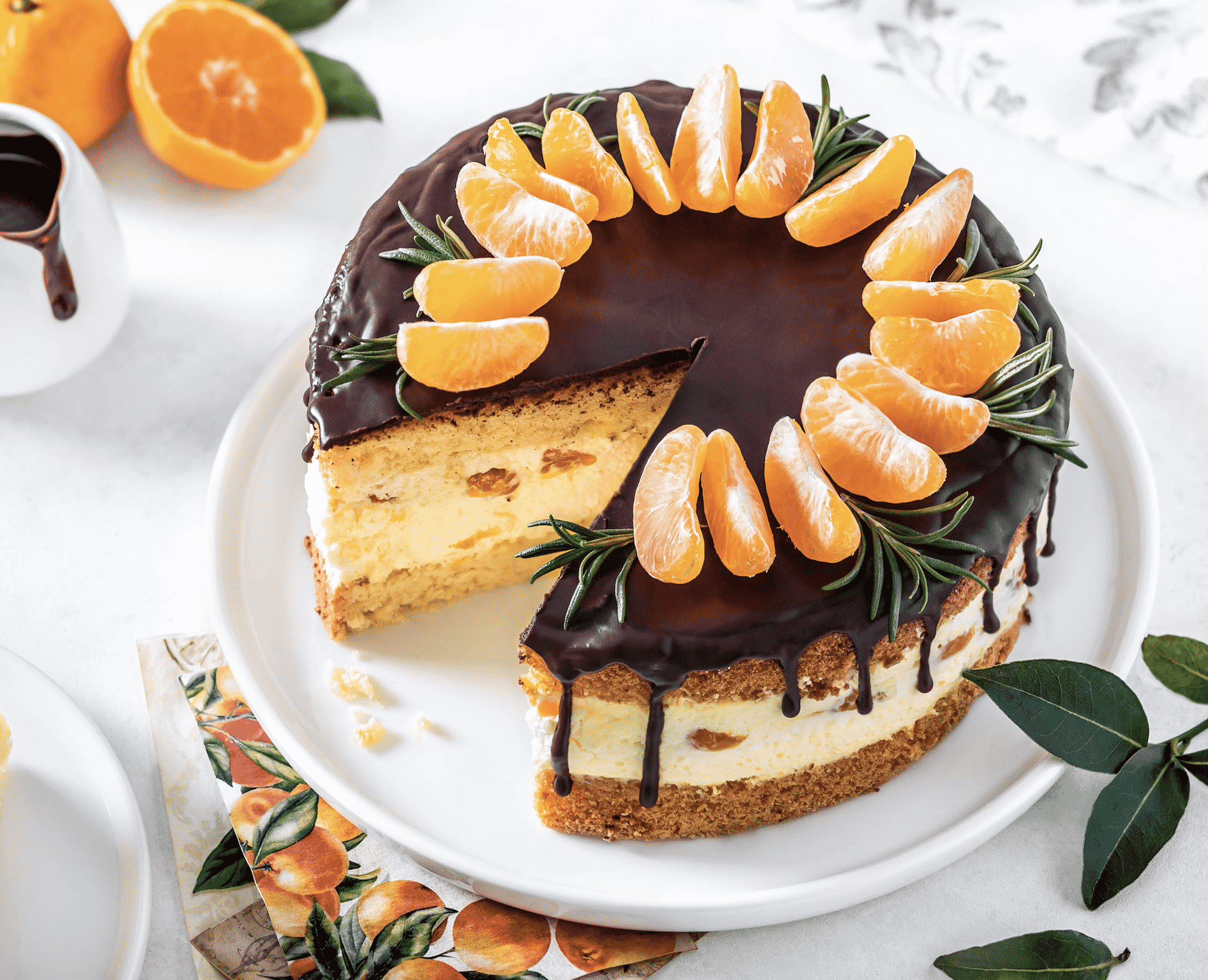 Mandarin mousse cake on a white plate with mandarins decorating the top.